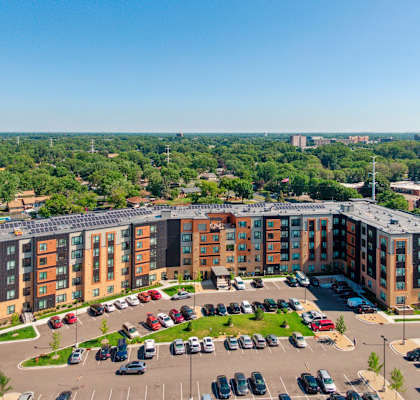 A large apartment complex with a parking lot in front at Sonder Point 50+ Apartments, Brooklyn Center, MN, 55430