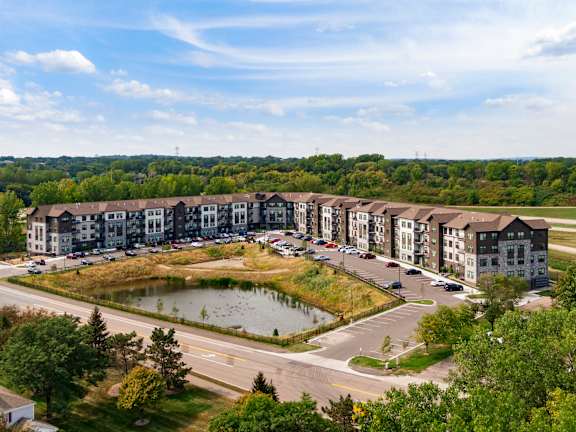 A large apartment complex with a pond in the front yard.