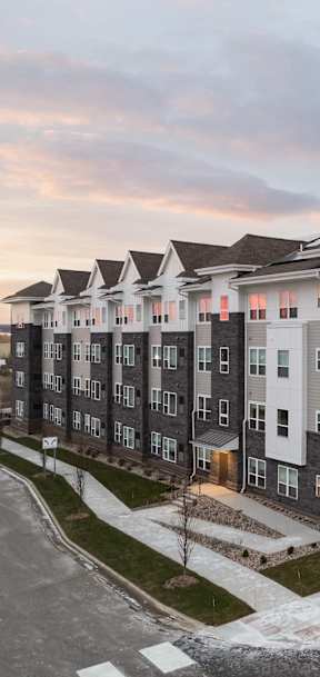 A large apartment complex with multiple buildings and a parking lot in front.