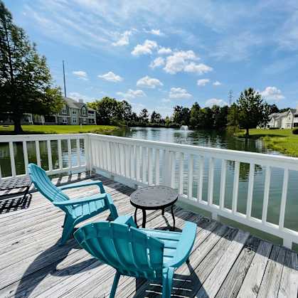 a deck with two chairs and a table on a body of water at The Chase, Burlington, NC