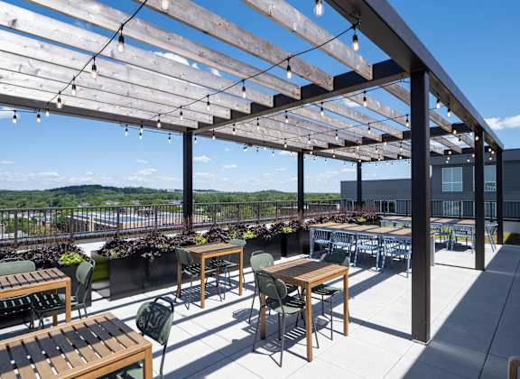 A patio with tables and chairs under a wooden pergola.