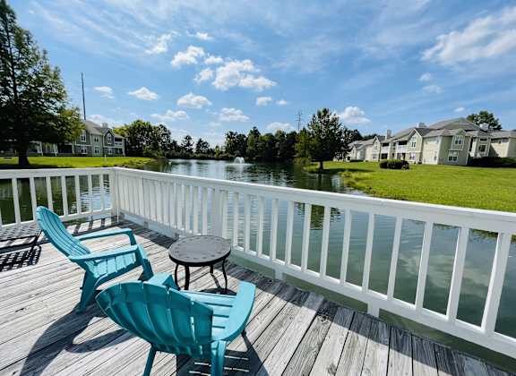 a deck with two chairs and a table on a body of water at The Chase, Burlington, NC