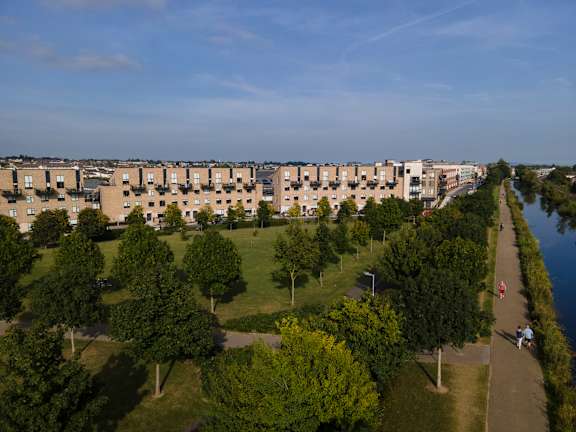 an aerial view of a park with trees and buildings in the background