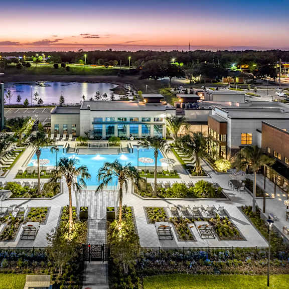 A beautifully lit resort with a pool at dusk.