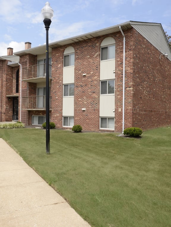 a brick apartment building with a lawn and a sidewalk at Fairbrook Park, Baltimore, 21244