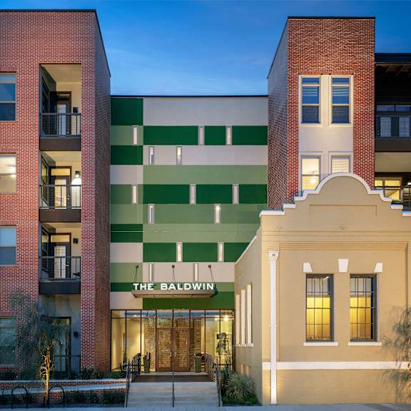Street-level view of an The Baldwin building with a mix of exterior materials, balconies, and landscaped edges