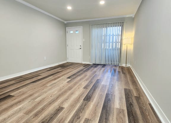 a living room with hardwood flooring and a door to a bedroom
