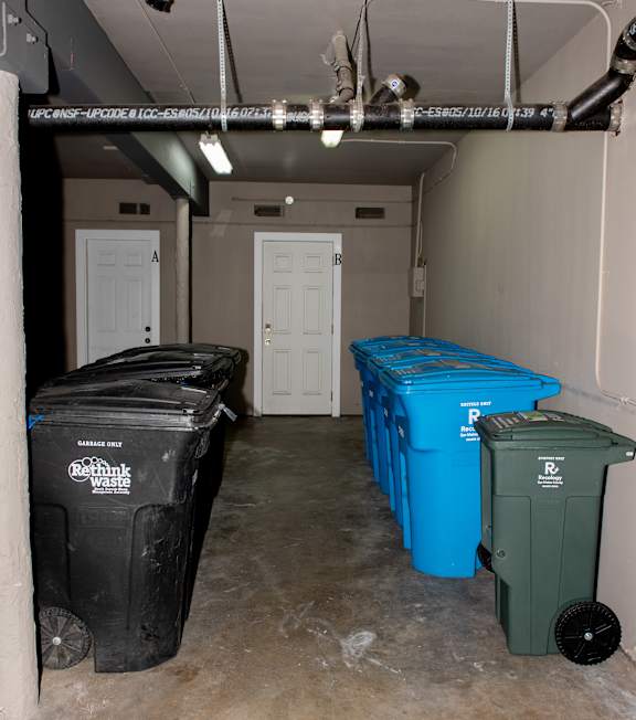 A row of white front loading washing machines are lined up in a laundromat.