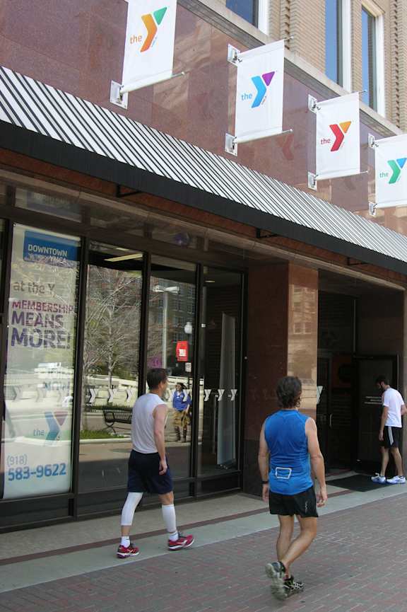 Two men are walking past a YMCA building.