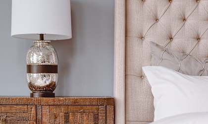 a bedroom with a bed and a wooden nightstand with a lamp on it