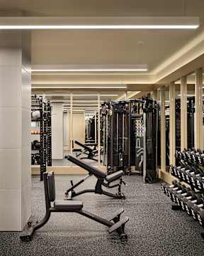 A gym with a variety of equipment including weights and benches.