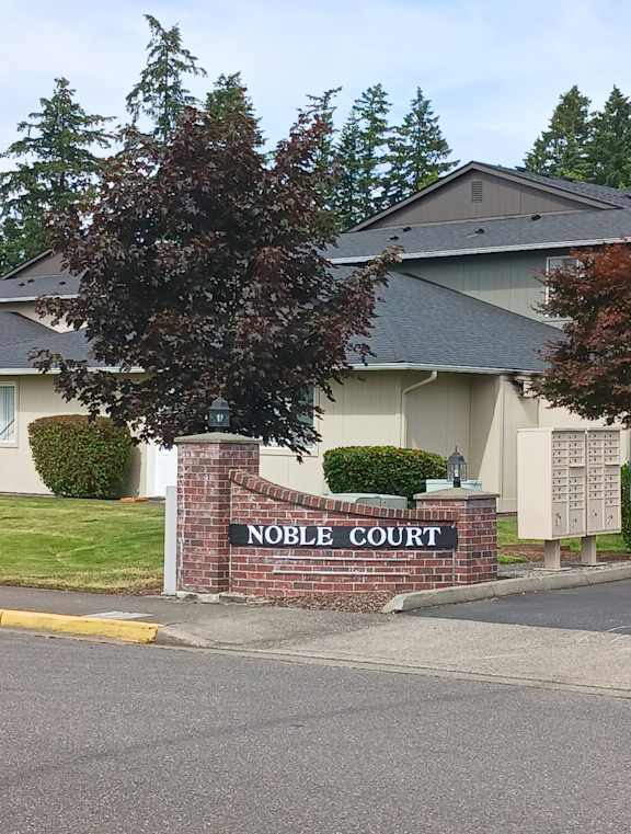A sign that says Noble Court stands in front of a building.