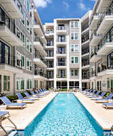 A large swimming pool in front of a multi-story residential building.
