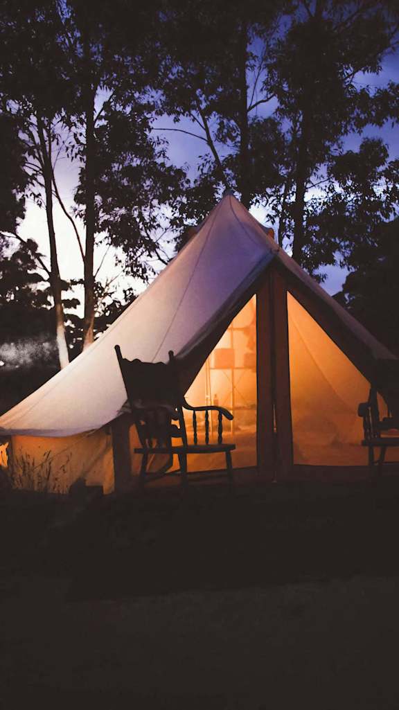 a tent lit up at night in the woods
