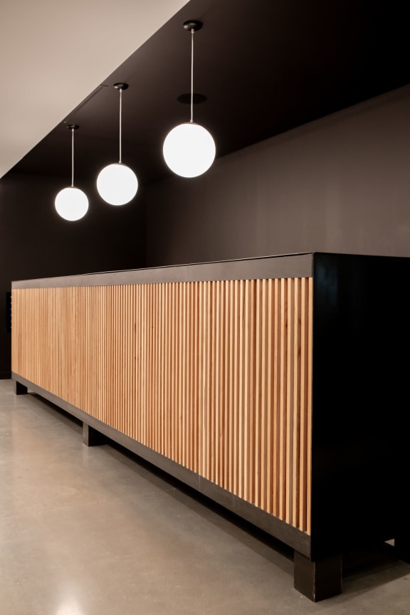 a long wooden wall with three lamps hanging above it and a black