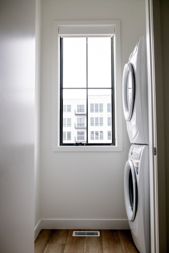 stacked laundry machines in bright room with large windows