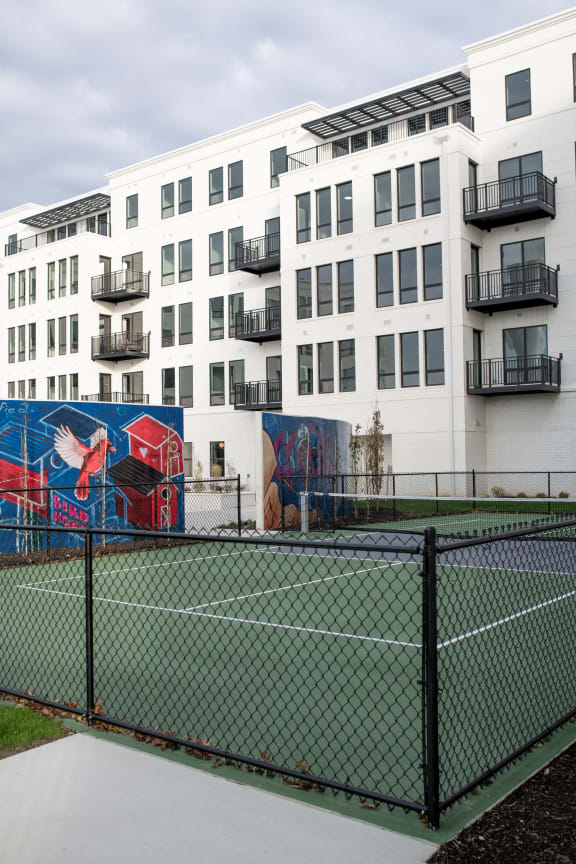 a tennis court in front of a building with graffiti on it