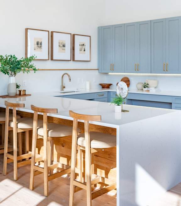 A kitchen with a white counter and blue cabinets.