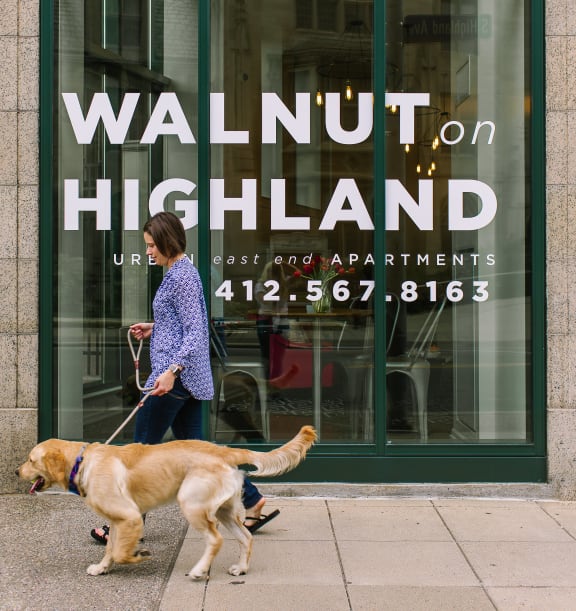 a woman walking her dog in front of a walnut highland store