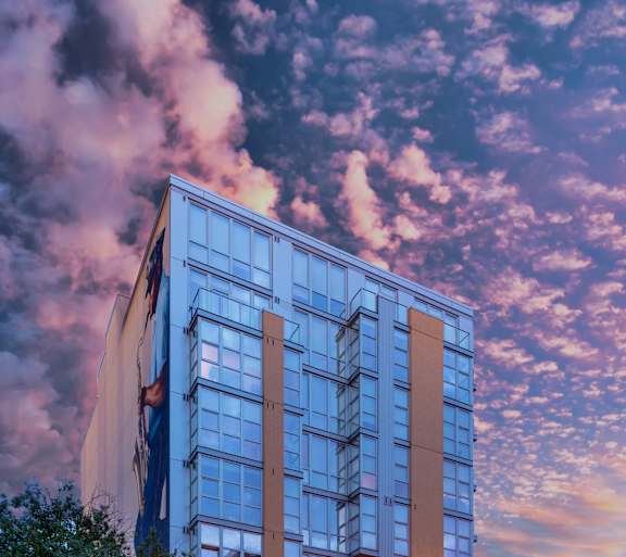 A modern glass building stands tall in the cityscape at dusk.