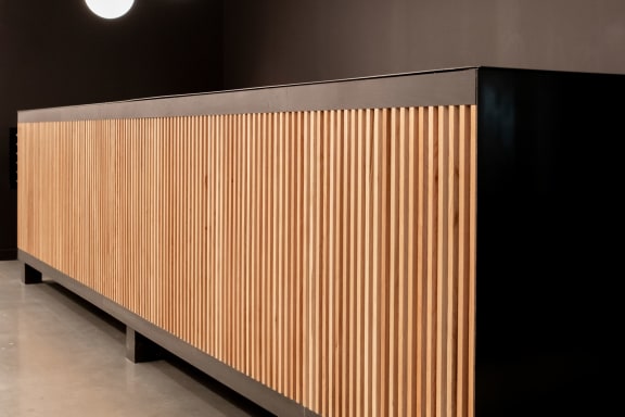 a long wooden wall with three lamps hanging above it and a black