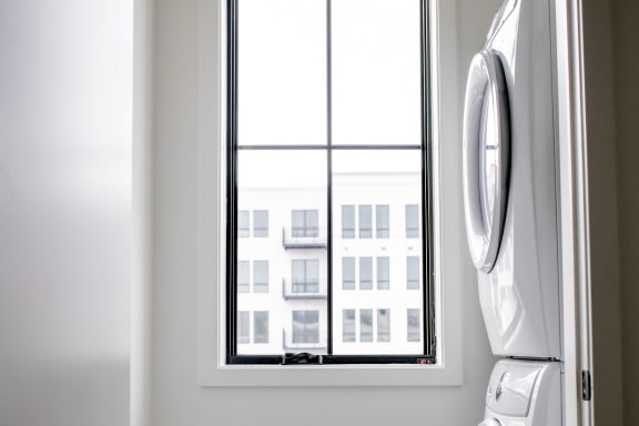 stacked laundry machines in bright room with large windows