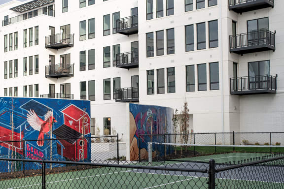 a tennis court in front of a building with graffiti on it