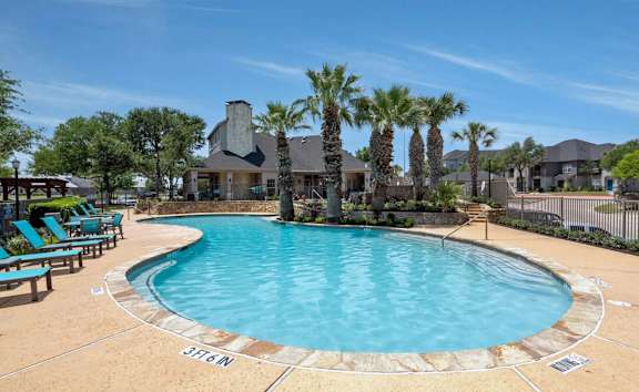 A large swimming pool surrounded by palm trees and lounge chairs.