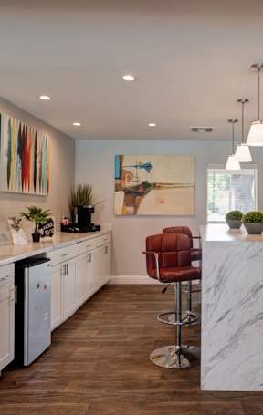A modern kitchen with a marble island and a dining area with a table and chairs.