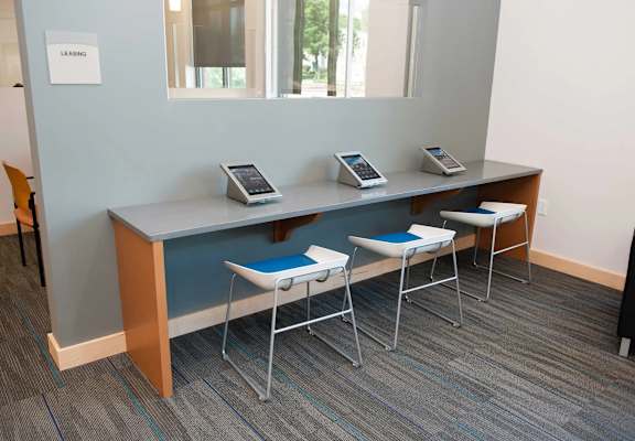 A row of three desks with chairs and phones on them.