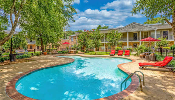 A swimming pool surrounded by a red brick border with a building in the background.
