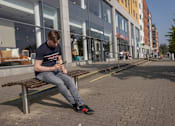 Thumbnail 6 of 8 - a man sitting on a bench looking at his cell phone