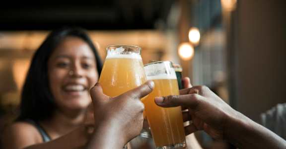 Two people toasting with glasses of beer.