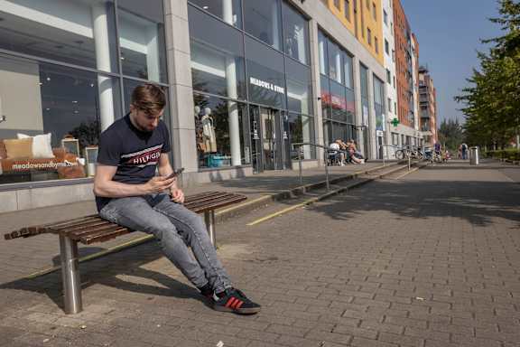 a man sitting on a bench looking at his cell phone