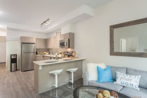 a living room with a couch and a kitchen with a bar and stools