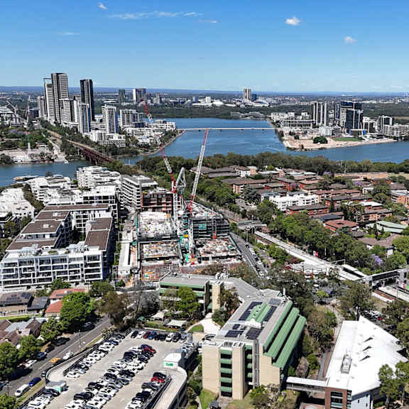 A cityscape with a large body of water in the foreground and a bridge in the background.