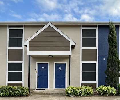 a building with two blue doors and a tree in front of it