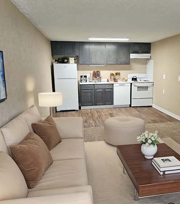 A modern living room with a couch, coffee table, and a kitchen in the background.