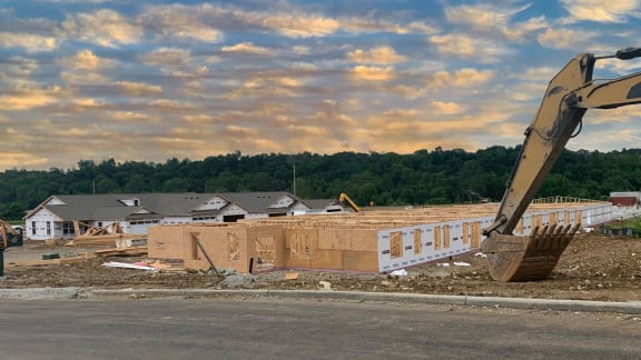 a building being constructed with an excavator in the foreground