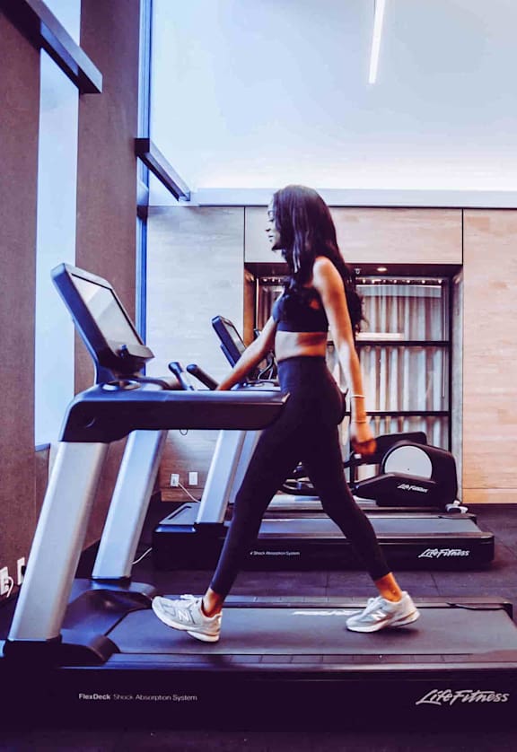 a woman running on a treadmill in a gym
