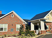 Thumbnail 5 of 5 - a brick house with a black roof and a street in front