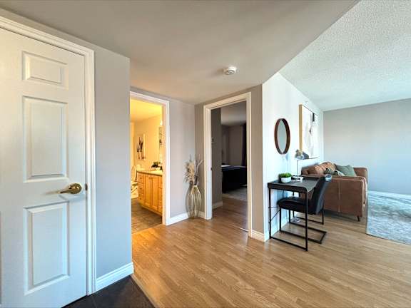 A modern kitchen with a stainless steel refrigerator and wooden flooring.