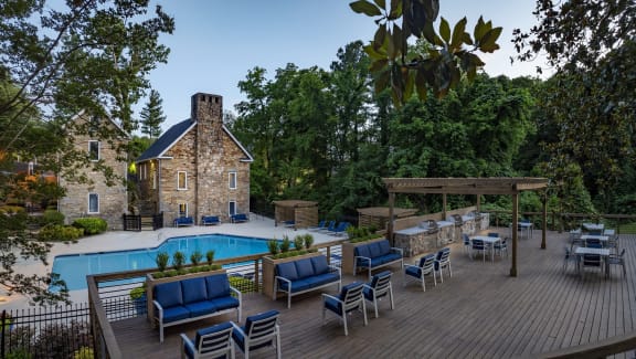 a backyard with a swimming pool and a patio with blue chairs and a barbecue