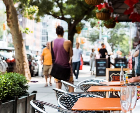 People walking by cafe with plants