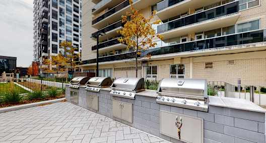A row of outdoor grills are lined up on a patio.