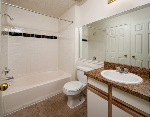 A bathroom with a white tub, toilet, and sink.