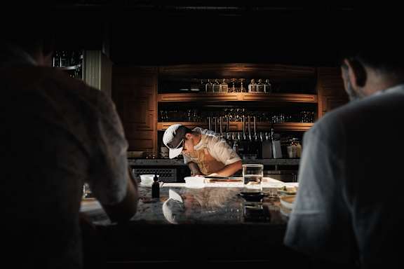 A bartender is making a drink at the bar.