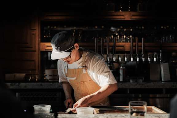 A chef in a white hat and apron is preparing food in a kitchen.