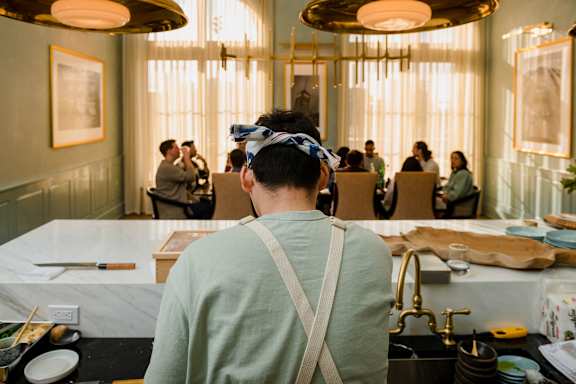 A man in a green shirt is sitting at a table in a restaurant.