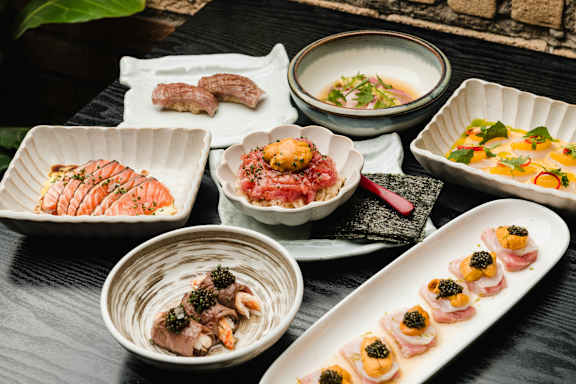 A variety of Japanese dishes are neatly arranged on a dark wooden table.